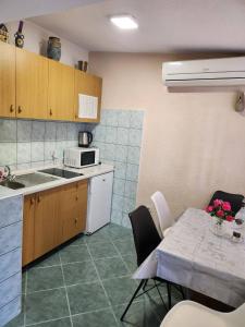 una cucina con tavolo, lavandino e forno a microonde di Apartman Gabriel a Podgora