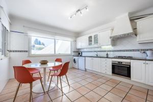 uma cozinha com armários brancos e uma mesa e cadeiras em Casa Melancia na Praia da Luz