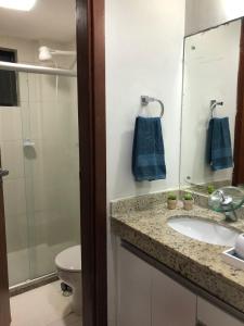 a bathroom with a sink and a toilet and a mirror at Cobertura Armação in Salvador