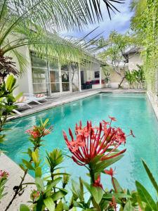 a swimming pool with a red flower in front of a house at The Decks Bali in Legian