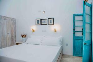a bedroom with a white bed and a blue door at Mawella House 1807, Tangalle in Tangalle