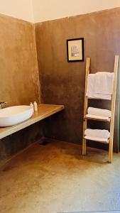 a bathroom with a sink and a shelf with towels at Mawella House 1807, Tangalle in Tangalle