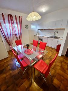 a dining room with a table and red chairs at Apartments Cacija in Trogir