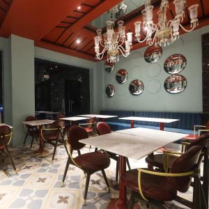 a dining room with tables and chairs and a chandelier at The Saga Hotel in New Delhi