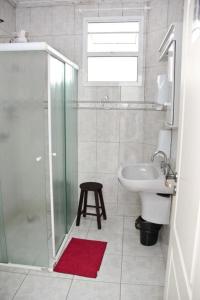 a bathroom with a shower and a sink and a stool at Joshua Tree Hostel - Curitiba in Curitiba