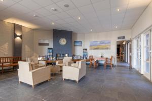 een wachtkamer met stoelen en tafels en een klok bij Fletcher Badhotel Callantsoog in Callantsoog