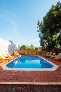 a swimming pool in a yard with chairs and a fence at Palma Real Bungalow in Puerto Iguazú