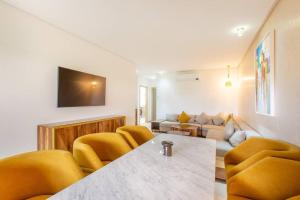 a living room with a table and yellow chairs at Résidence Golfique PJ, jardin, piscine in Marrakesh