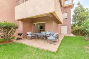 a patio with a table and chairs in a yard at Résidence Golfique PJ, jardin, piscine in Marrakesh