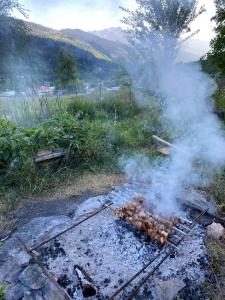 a grill with smoke coming out of it in a field at Roza's guest house in Mestia
