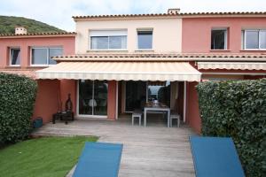 uma casa com um pátio e duas cadeiras azuis em Ajaccio maison bord de mer dans résidence avec piscine em Ajaccio