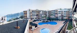 a large apartment building with a swimming pool and a resort at Casa Lea Los Gigantes in Puerto de Santiago