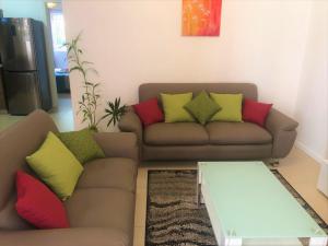 a living room with a couch with colorful pillows at Pereybere Holiday Apartment in Pereybere