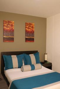 a bedroom with a bed with blue and white pillows at hotel medellin gold in Medellín