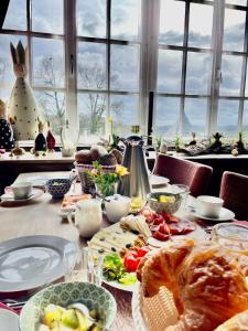 a table with plates of food on a table with windows at Burghaus & Villa Kronenburg in Kronenburg