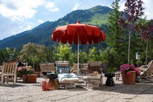 eine Gruppe Stühle und ein Sonnenschirm auf einer Terrasse in der Unterkunft Kristiania Lech in Lech am Arlberg