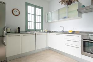 kuchnia z białymi szafkami i zegarem na ścianie w obiekcie Hommyhome Castellar Luxury w Sewilli