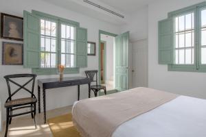 sypialnia z łóżkiem, biurkiem i oknami w obiekcie Hommyhome Castellar Luxury w Sewilli