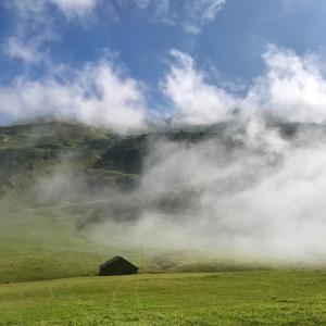 a foggy field with a barn in front of a mountain at Kristiania Lech in Lech am Arlberg