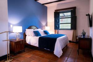 una camera da letto con un letto con pareti blu e una finestra di Hotel Hacienda Supracafe a Popayan