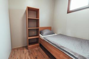 Dormitorio pequeño con cama y estante de libros en Terme Banovci - Mobilne hiške Med Brajdami, en Banovci