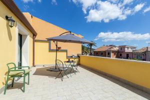 eine Terrasse mit einem Tisch, Stühlen und einem Sonnenschirm in der Unterkunft Belvedere 3 in Piedimonte Etneo