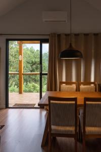 uma sala de jantar com uma mesa e uma grande janela em Cabana Serra Grande Sossego em Gramado