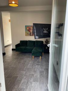 a living room with a green couch and a television at Byelands Lodge in Middlesbrough