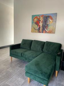 a green couch in a living room with a painting of an elephant at Byelands Lodge in Middlesbrough