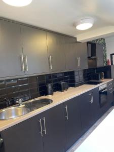 a kitchen with black cabinets and a sink at Byelands Lodge in Middlesbrough