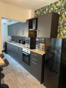 a kitchen with gray cabinets and a black refrigerator at Byelands Lodge in Middlesbrough