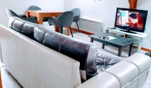 a living room with a leather couch and a television at Chambres Du Petit Bonheur in Biscarrosse