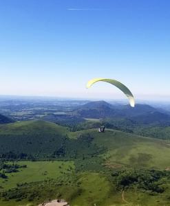 a person riding a parachute in the sky at La terrasse des volcans in Saint-Genès-Champanelle