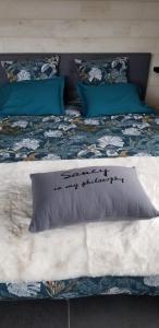 a bed with a pillow with writing on it at La terrasse des volcans in Saint-Genès-Champanelle