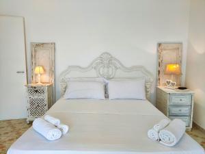 Un dormitorio con una cama blanca con toallas. en La Caura di Casa Camilla Journey en Marina Serra