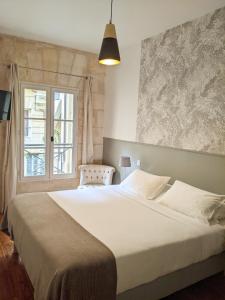 Un dormitorio con una gran cama blanca y una ventana en L'Apparthôtel Particulier Bordeaux, en Burdeos