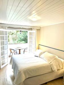 a bedroom with a bed and a table and a window at Pousada Morro do Elefante in Campos do Jordão