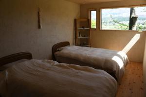 two beds in a room with a window at 青い空と白い龍 in Minami Aso
