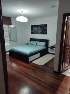 um quarto com uma cama e piso em madeira em Piso a pie de playa em Vilagarcía de Arousa