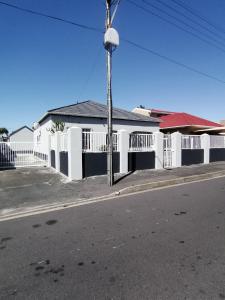 a white house with a white fence and a street at Mila Lodge 1 in Cape Town