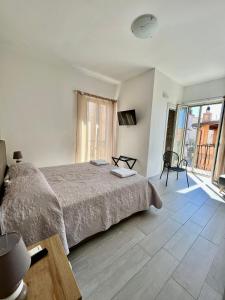 a white bedroom with a bed and a large window at La Dependance ApartHotel Scilla in Scilla