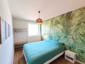 a bedroom with a blue bed and a palm mural at L'Horizon in Bergheim