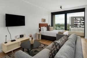 sala de estar con sofá, TV y cama en Newlands Peak Aparthotel by Totalstay, en Ciudad del Cabo