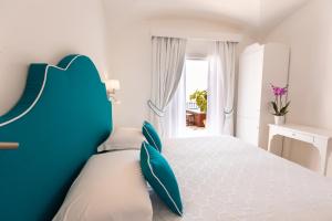 una camera da letto bianca e blu con un grande letto di Hotel Conca d'Oro a Positano