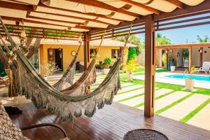 an outdoor patio with hammocks and a house at Casa em cond fechado em Barra de Santo Antonio AL in Barra de Santo Antônio