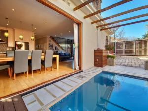 uma imagem de uma casa com uma piscina e uma sala de jantar em Cottage 8 Virginia Avenue em Cidade do Cabo