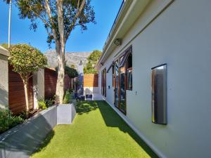 a yard with green grass next to a house at Cottage 8 Virginia Avenue in Cape Town