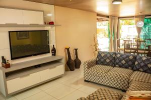 a living room with a couch and a flat screen tv at Casa em cond fechado em Barra de Santo Antonio AL in Barra de Santo Antônio