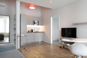 a kitchen with white cabinets and a table and a television at Brera Serviced Apartments Munich West in Munich