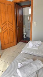 a room with two beds and a bathroom with a toilet at Artemis Hotel Apartments in Keramotí